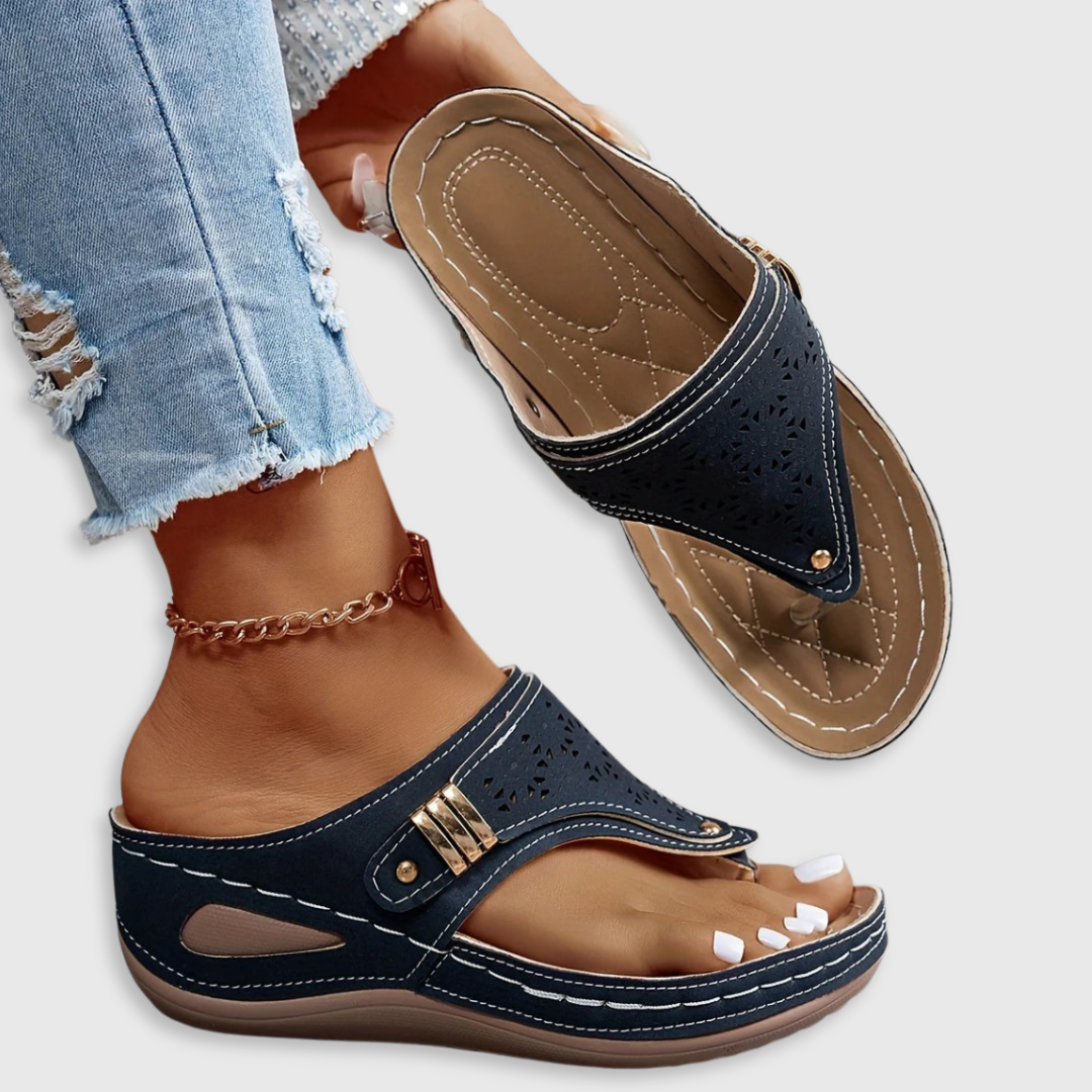Navy Jean sandals with perforated strap, adjustable buckle, and cushioned sole.