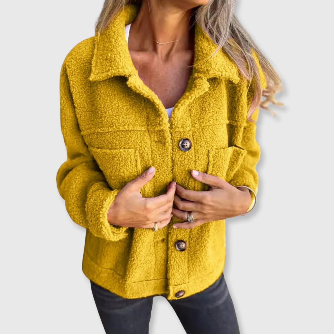 Yellow sherpa-style coat with button closure and chest flap pockets, worn open at front.