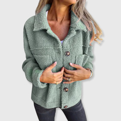 Green sherpa-style coat with button closure and two flap pockets, worn open at front.