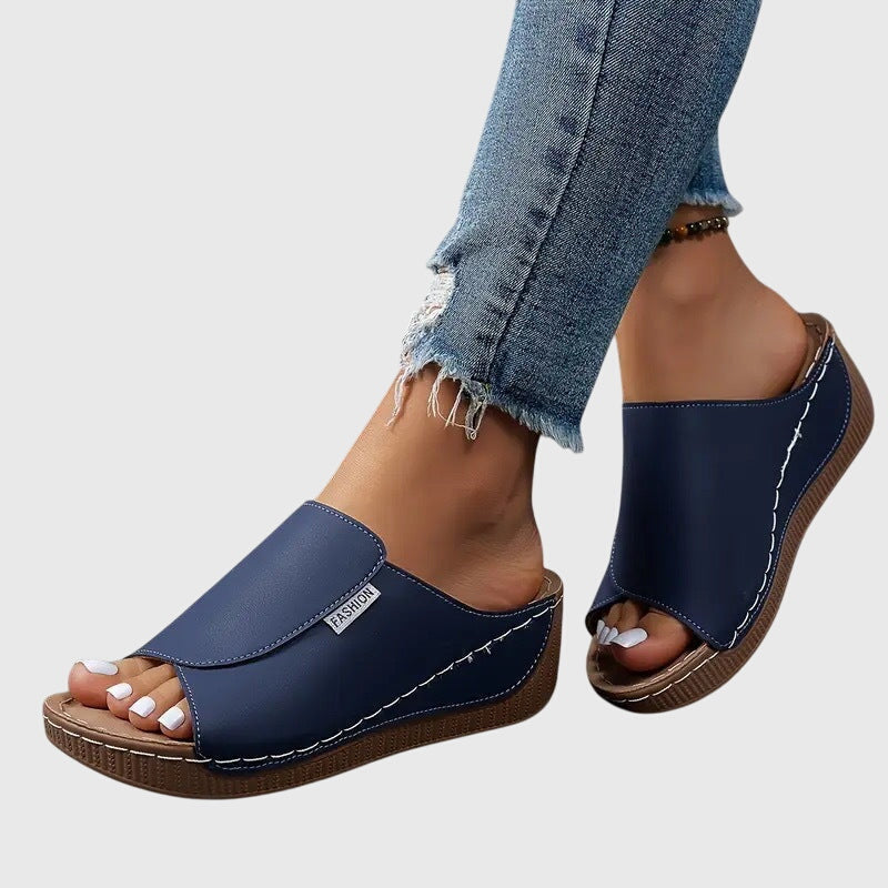 Navy blue wedge sandals with wide strap and open toe, stitched trim and textured sole
