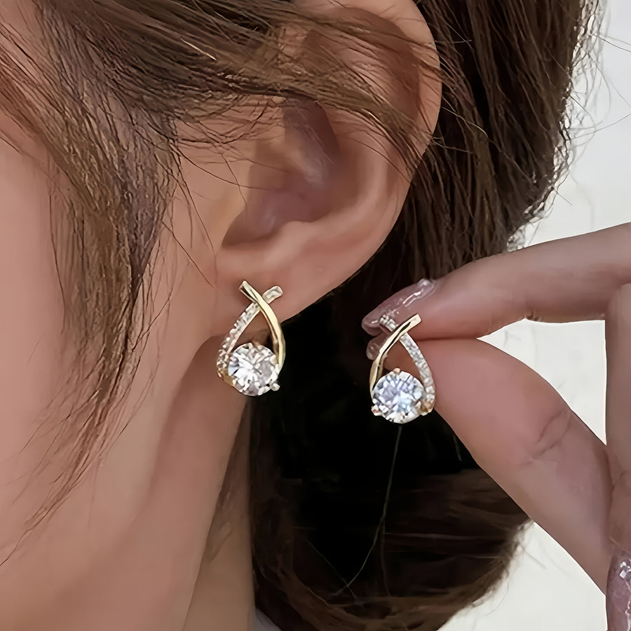 Gold-tone earrings on model ear, featuring round crystal centers and small top studs