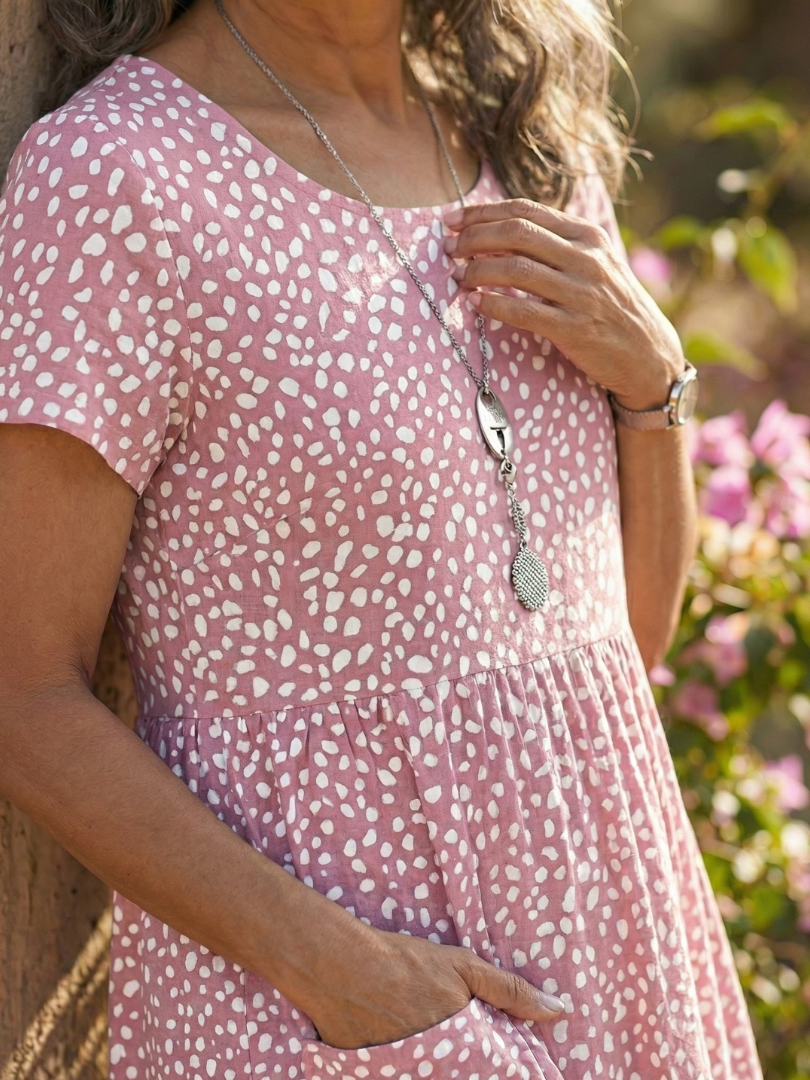 Pink Meadow Drift dress close-up: dotted fabric, gathered waist, short sleeves
