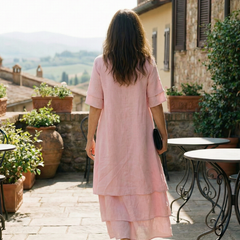 Pink tiered midi dress from back with short sleeves and black clutch