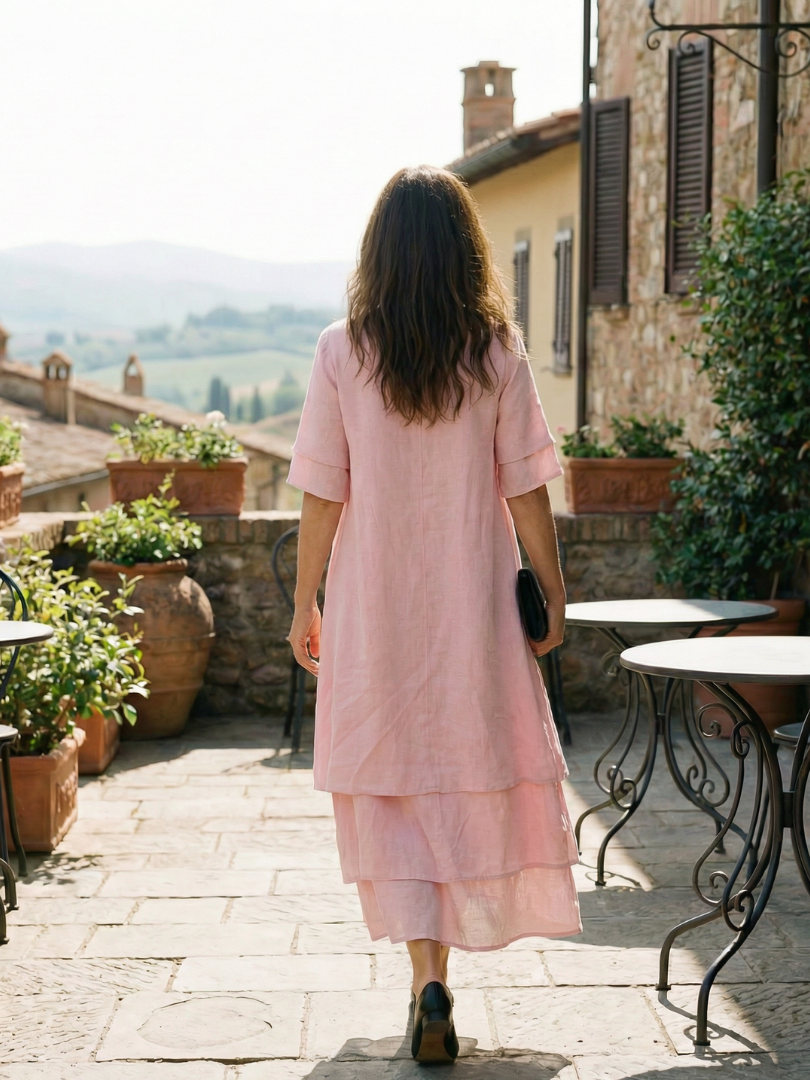 Pink tiered midi dress from back with short sleeves and black clutch