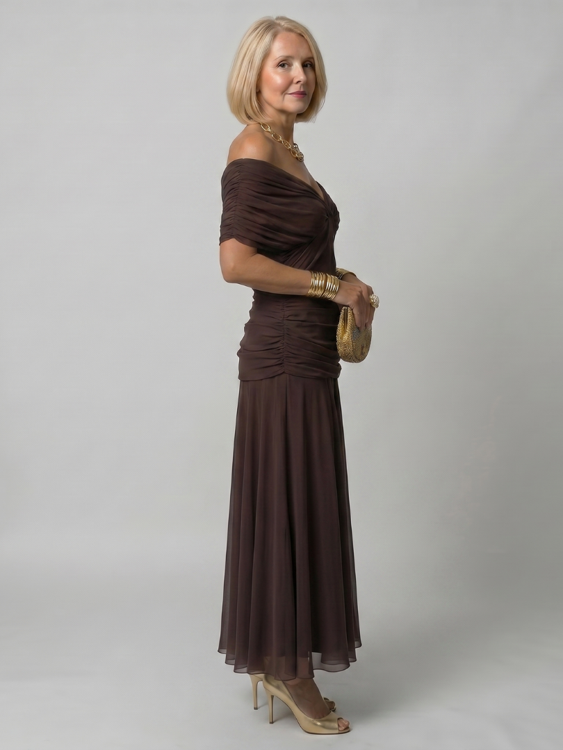 Off-shoulder flow maxi dress in dark brown, side view with draped neckline and pleated skirt