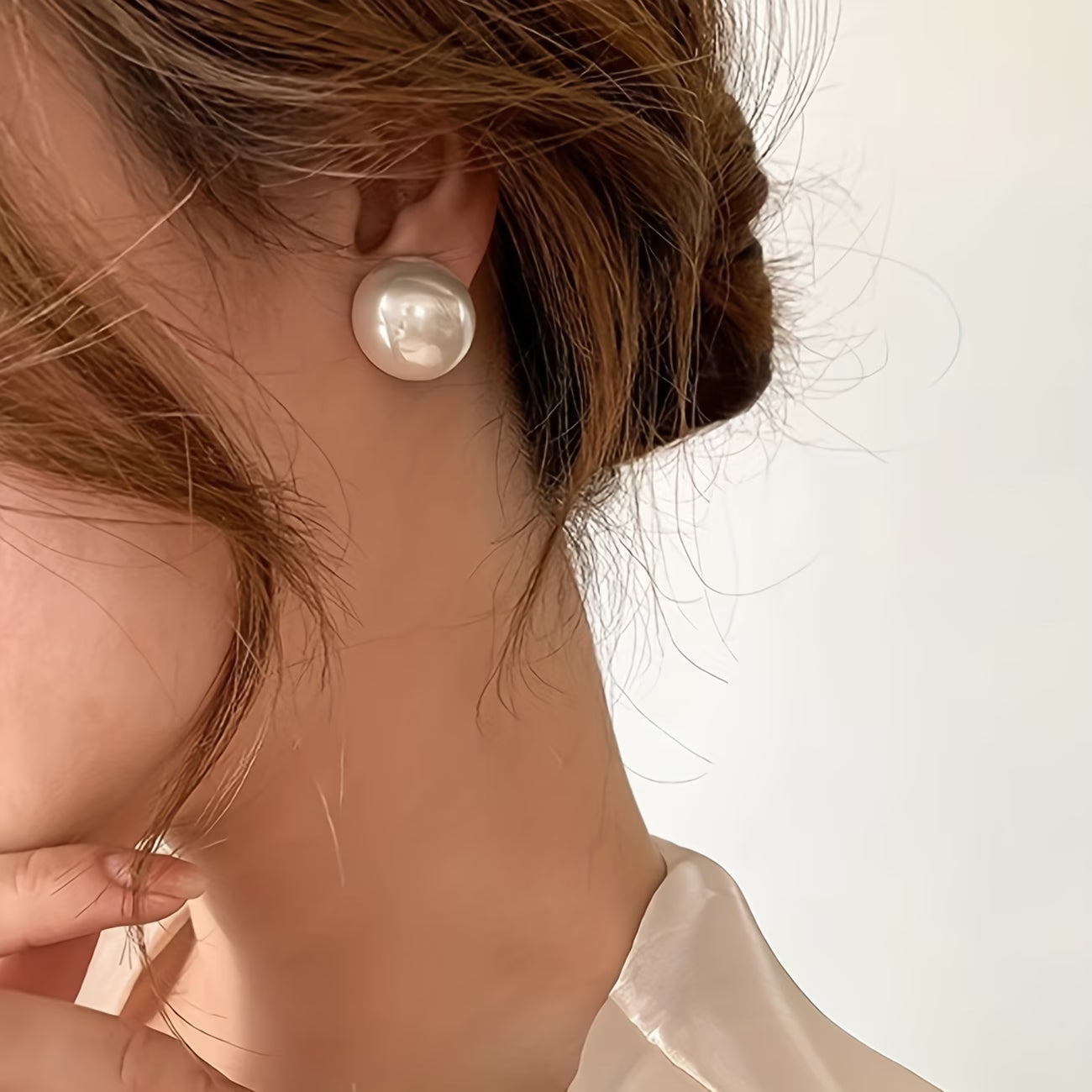 Pearl stud earrings on ear: large round white pearl stud