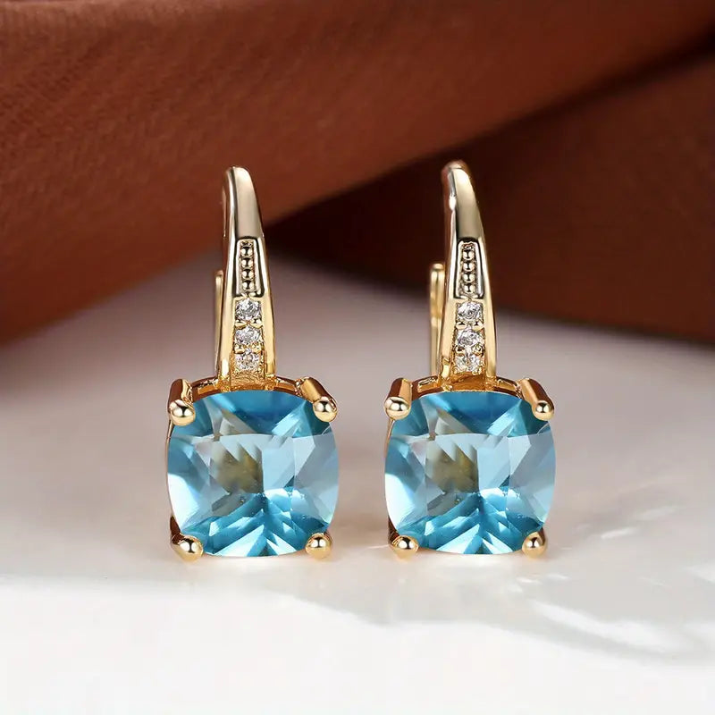 Gold hoop earrings with cushion-cut blue stones