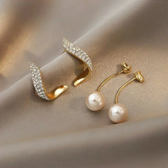 Gold-tone feather hoop earrings with crystal sparkle and white pearl drop detail.