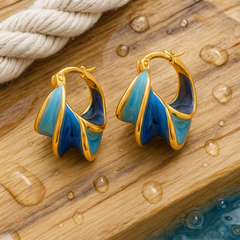 Close-up gold hoop earrings with blue wave enamel, glossy teardrop design