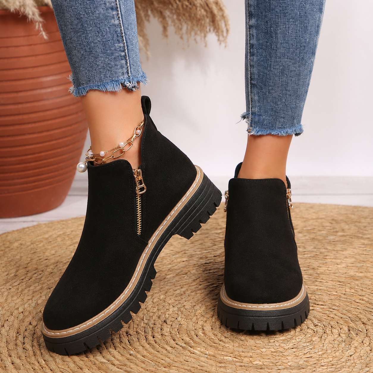 Women’s ankle boots in black suede with side zipper and lug tread sole.