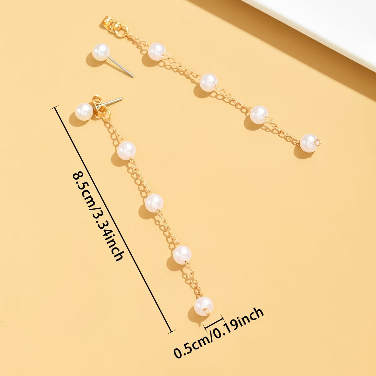 Gold-tone pearl dangle earrings, featuring dangling chain with round white pearls.