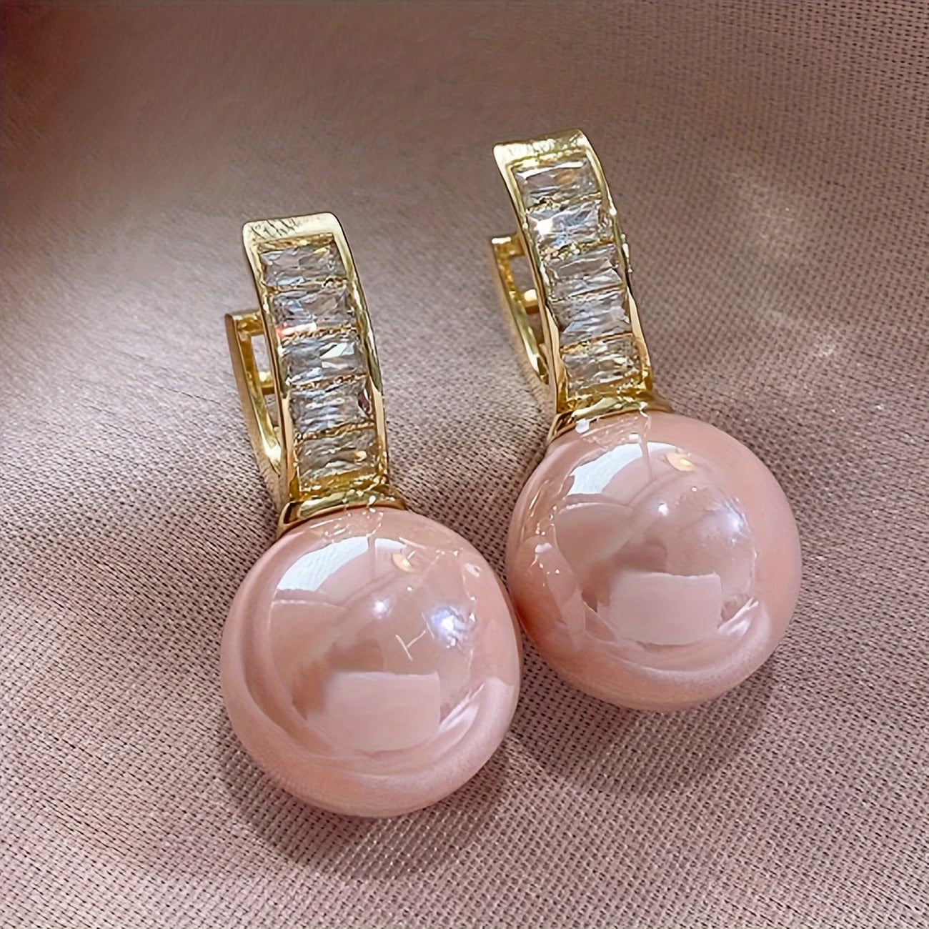 Gold hoop earrings with pink round pearl drops and clear baguette accents.
