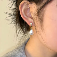 Gold hoop pearl drop earrings with white teardrop pearl on the ear