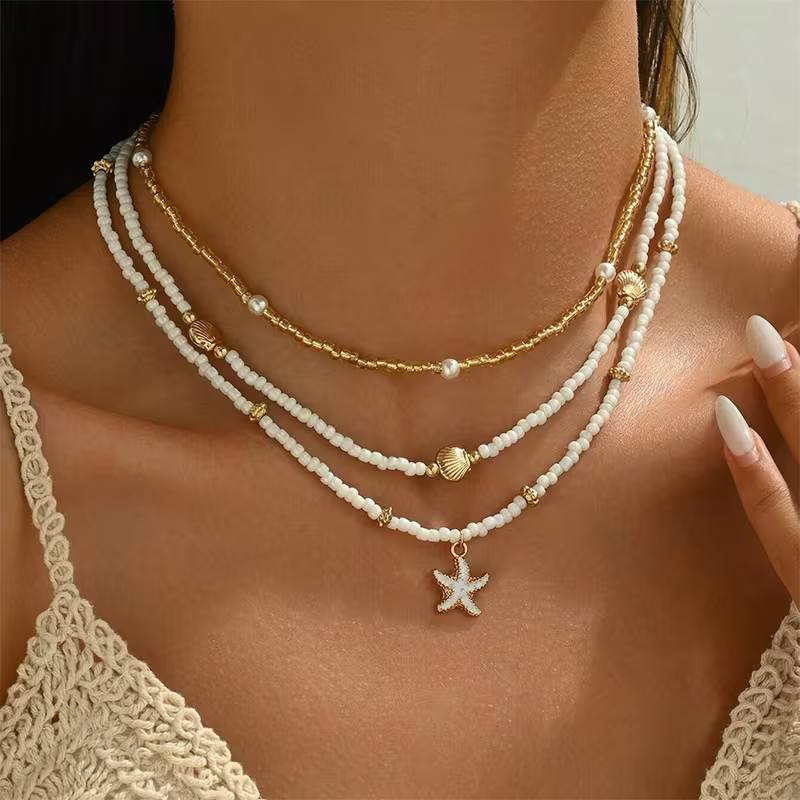 Layered necklace set with white bead strands and gold chain, starfish charm