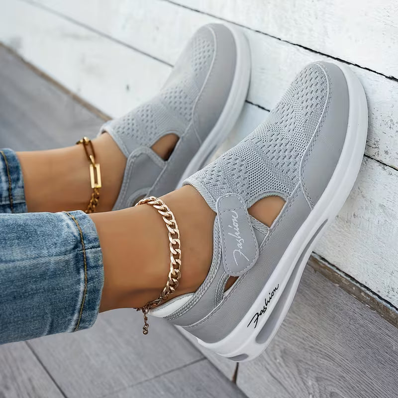Light gray perforated comfort sneakers with side cutout, elastic strap, and white sole