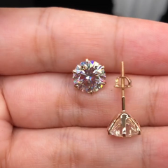 Gold-tone crystal stud earrings with round stones and small dangling charm detail