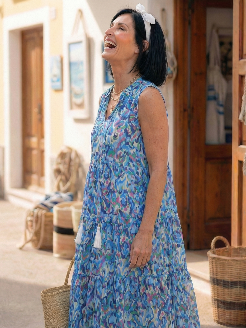 Blue sleeveless printed midi dress with V-neck, tassel accents, and flowing tiered hem