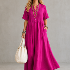Pink pleated maxi dress with V-neck and short sleeves, gathered waist.