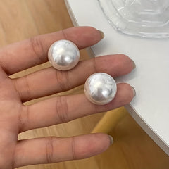 Pearl stud earrings close-up: round white pearl domes on posts