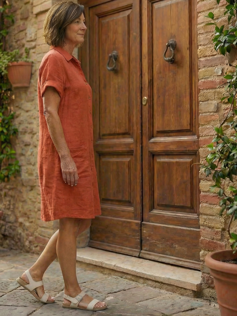 Orange linen-look courtyard walk dress in side profile with short sleeves and button front