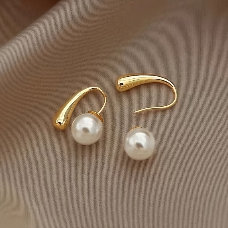 Gold arc hoop earrings with white pearl centers on posts, pair view