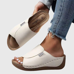 White wedge sandals with wide strap and open toe, stitched trim and textured sole