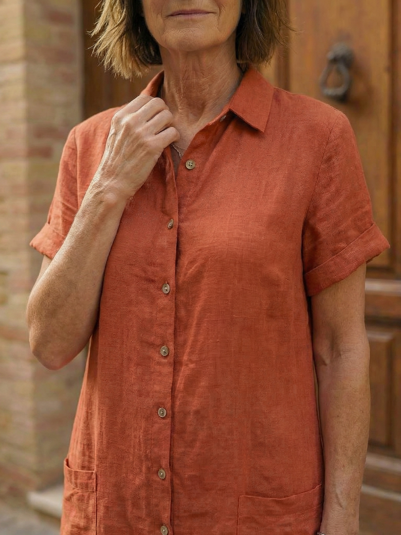 Close-up of orange linen-look courtyard walk dress: buttoned collar and short sleeves