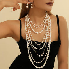 Multi-layer pearl statement necklace set with matching drop earrings on black top