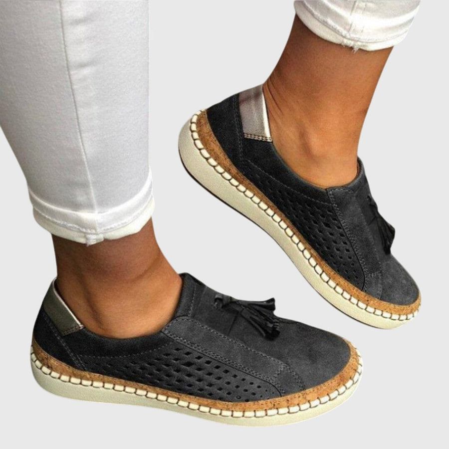 Black perforated comfort slip-on shoes with tassel detail and tan stitched sole