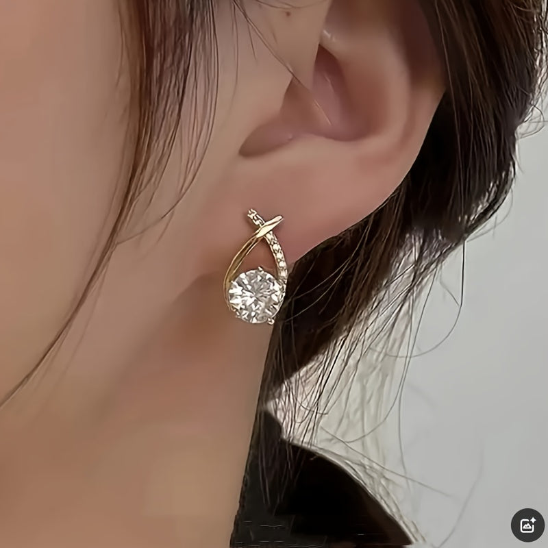 Gold-tone crystal drop stud earring on ear with pave-style side details