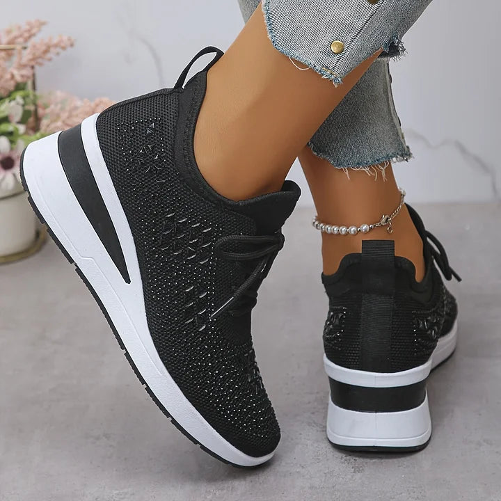 Black knit sneakers with lace-up front and white sole, rear view with heel tab