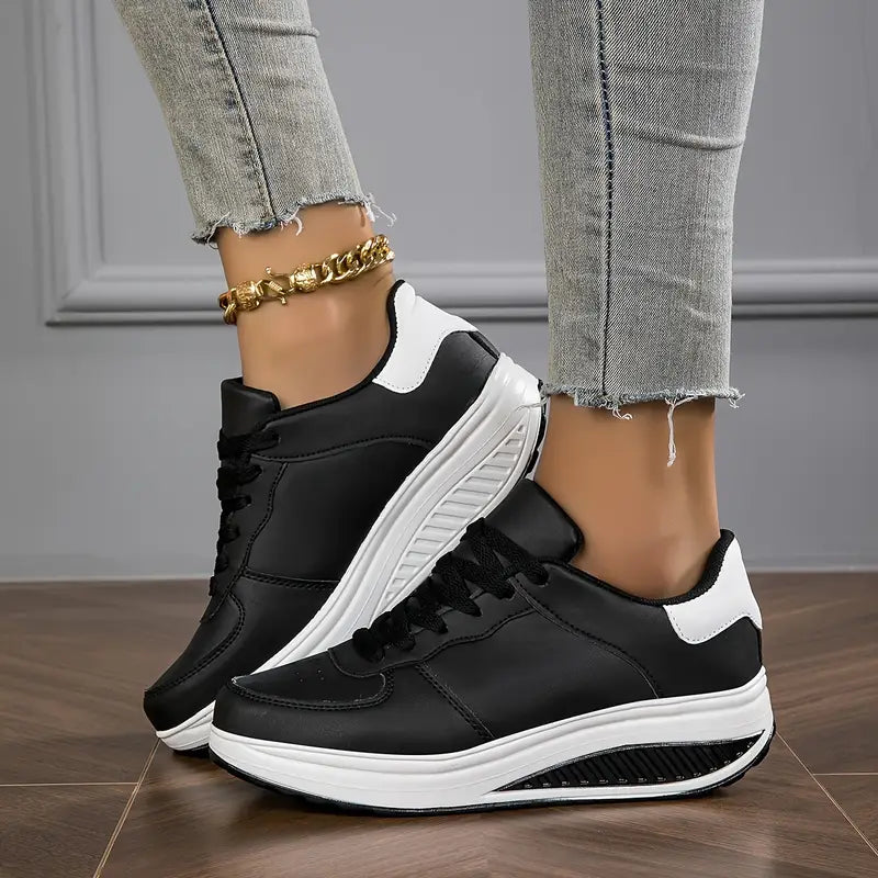 Black platform comfort sneakers with white accents and lace-up front on foot