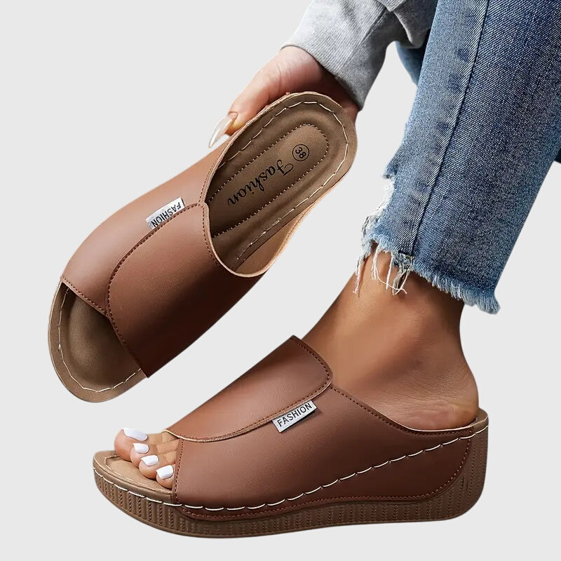 Brown wedge sandals with wide strap and open toe, stitched detail and textured sole