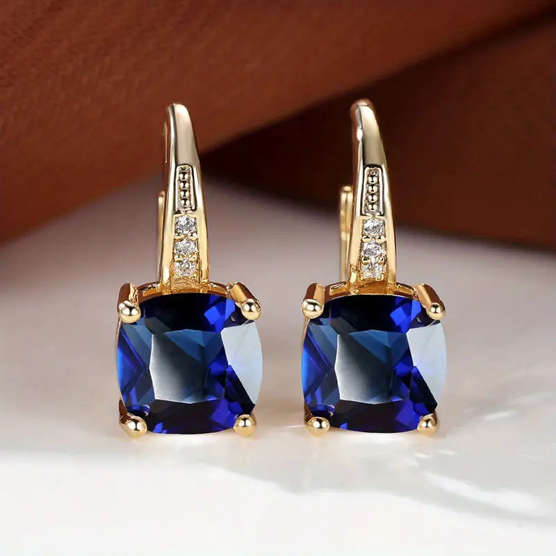 Gold hoop earrings with square blue gemstones and clear accent stones