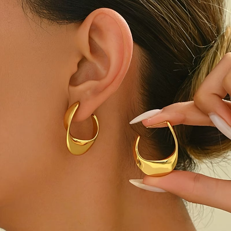 Gold twisted geometric hoop earrings, curved open ring design, close-up on ear