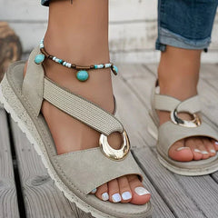 Beige flat sandals with ankle beaded strap and round gold-tone metal buckle