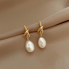 Gold hoop earrings with knotted links and white teardrop pearl drops
