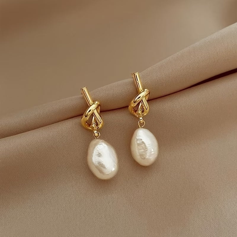 Gold hoop earrings with knotted links and white teardrop pearl drops