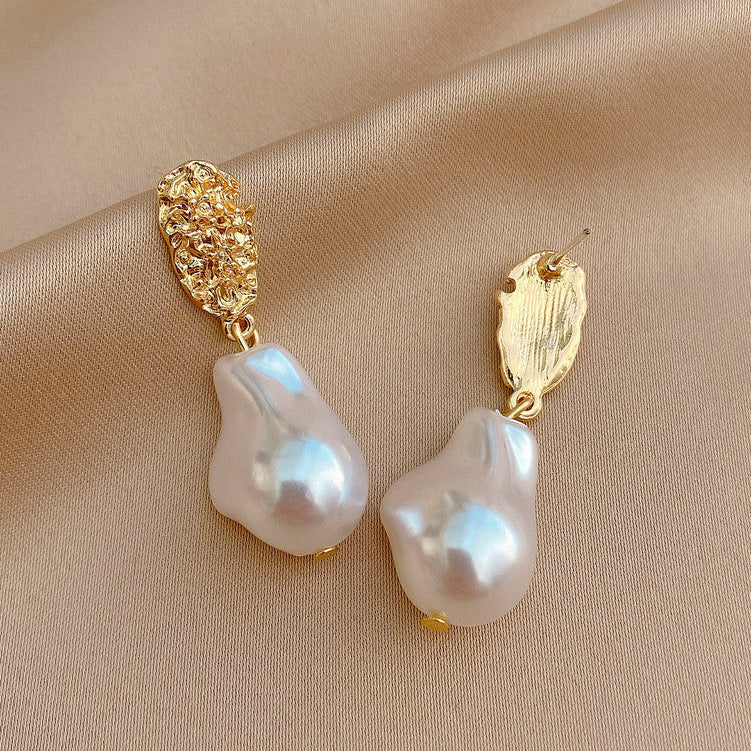 Gold drop earrings with white pearl teardrops and textured caps