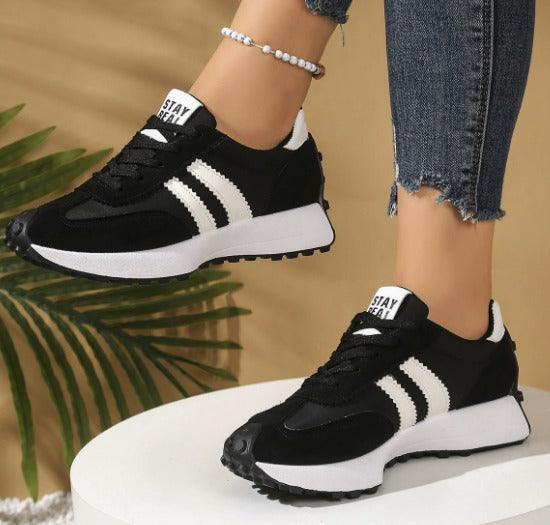 Black comfort sneakers with white side stripes and lace-up front, chunky sole