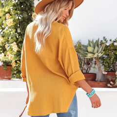 Yellow loose-fitting button-up blouse with long sleeves, shown from the side.