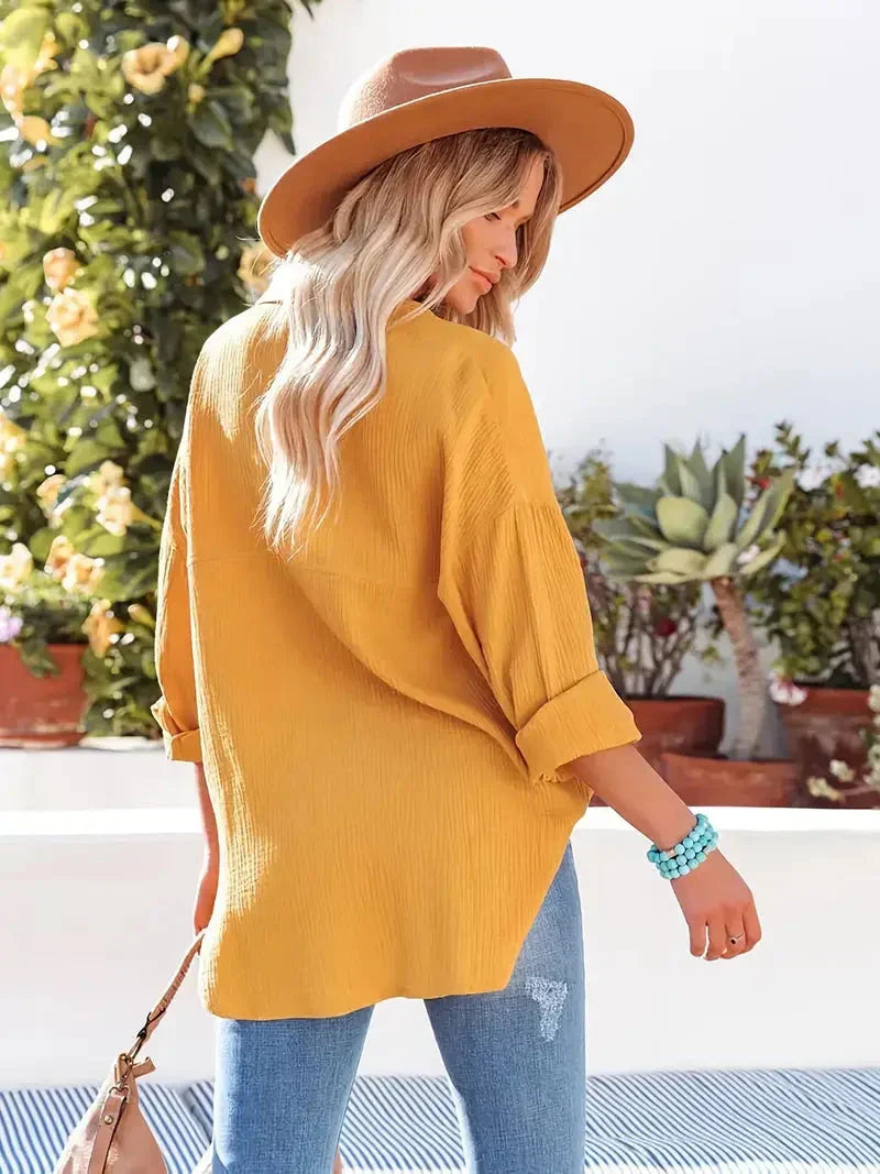 Yellow loose-fitting button-up blouse with long sleeves, shown from the side.