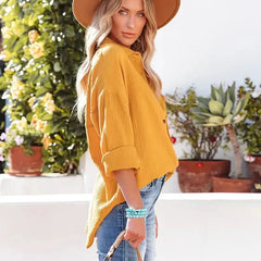 Yellow loose-fitting button-up blouse with long sleeves, side/back angle.