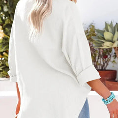 White loose-fitting button-up blouse with long sleeves, back view and side angle.