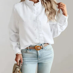 White button-up ruffle blouse with high neck and long sleeves, worn with jeans