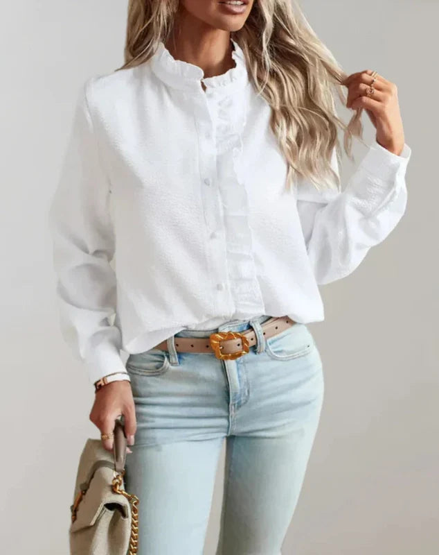 White button-up ruffle blouse with high neck and long sleeves, worn with jeans