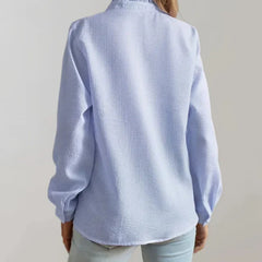 Light blue button-up blouse with long sleeves and collar detail, back view
