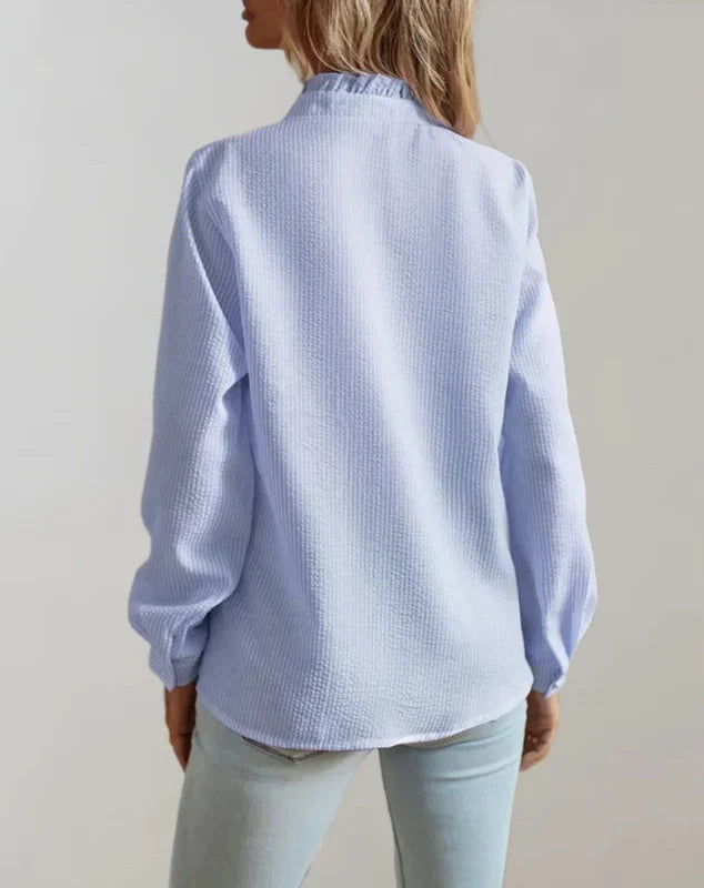 Light blue button-up blouse with long sleeves and collar detail, back view