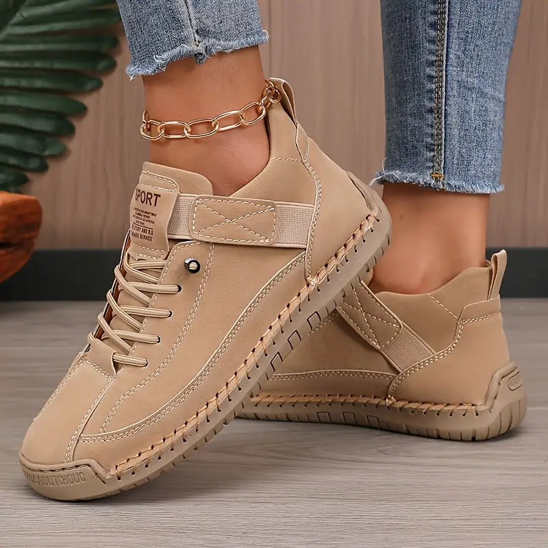 Beige comfort sneakers with lace-up front, side stitch details, and chain ankle strap