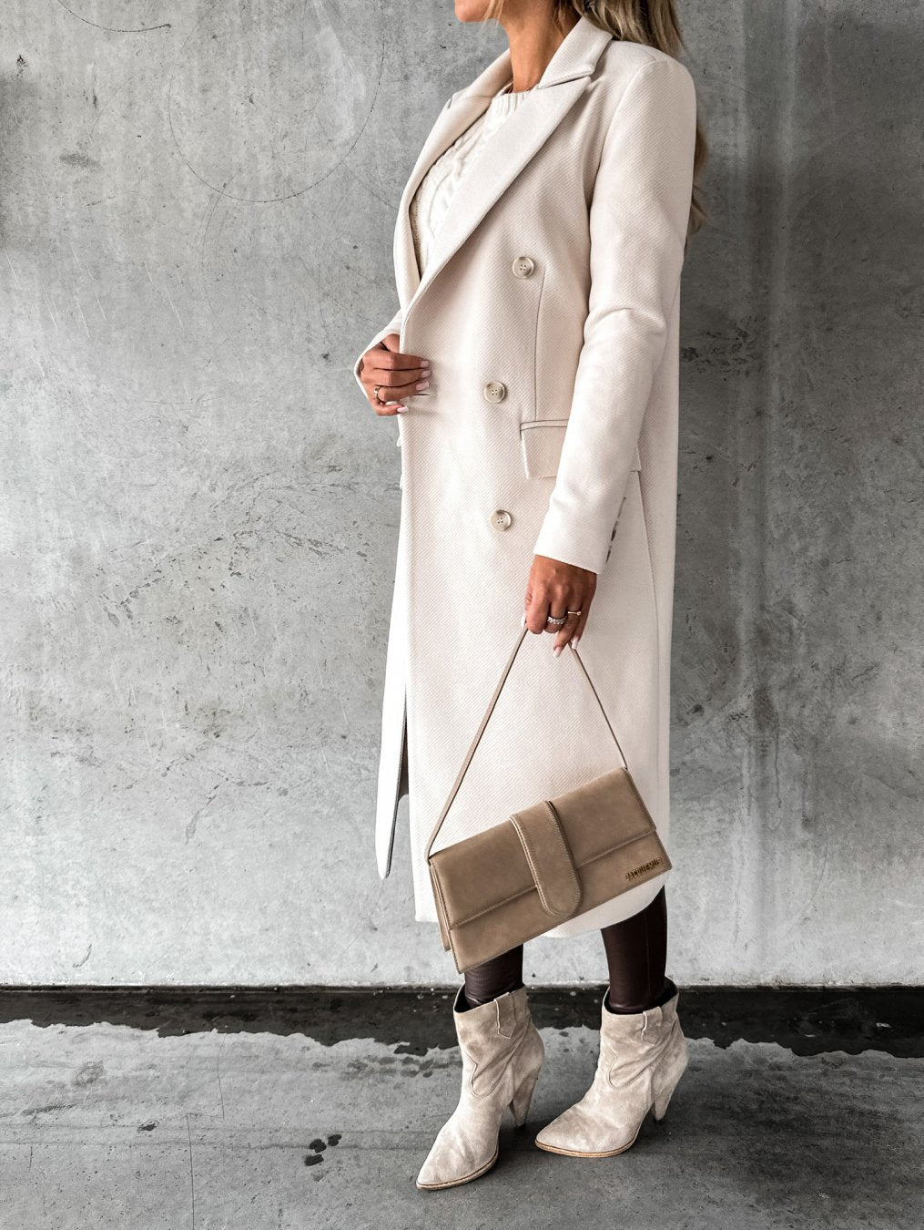 Cream long coat with notched lapel, double-breasted buttons, flap pockets, side view
